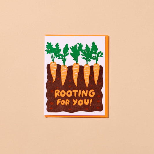 Greeting card with carrots and text 'Rooting for you!' on a beige background
