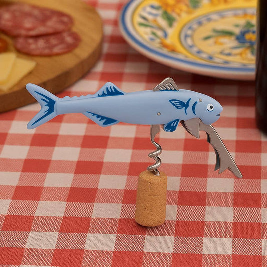 Fish-shaped corkscrew on a checkered tablecloth with a bottle and cork in the background.