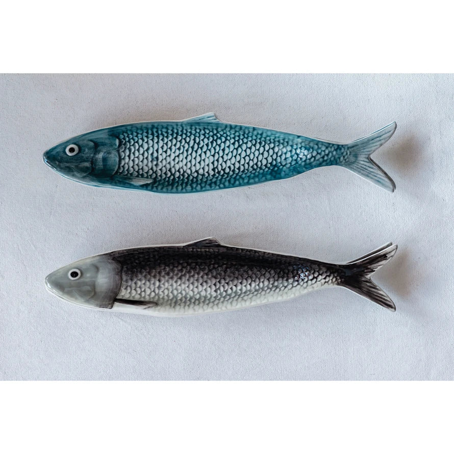 Two ceramic fish figurines on a white background, one with blue-green scales and the other with gray and silver scales.