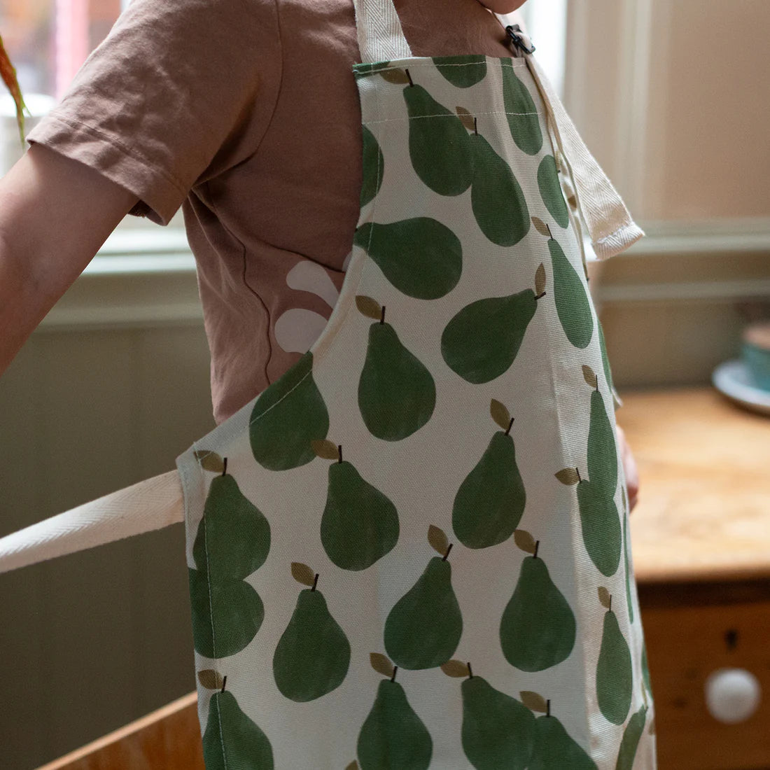 Close up photo -- Children sized apron with green pear print all over.