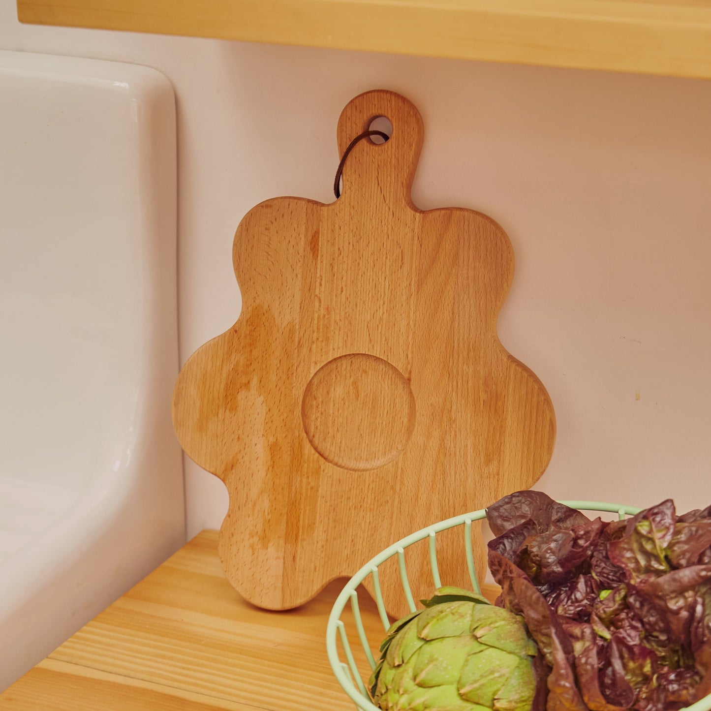 Floral shaped wooden cutting board standing against wall 