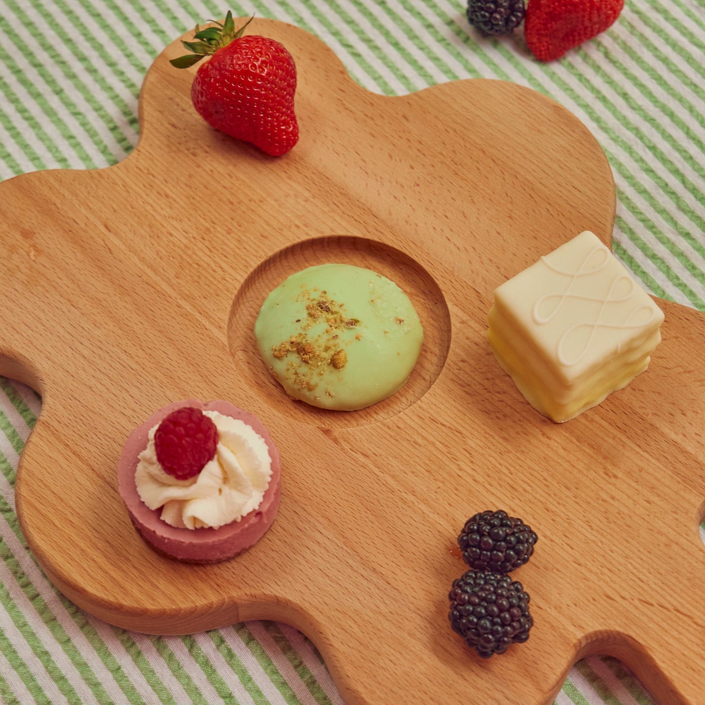 Floral shaped wooden cutting board with fruits and pastries on it 