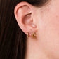 Close-up of an ear wearing gold hoop earring and a shrimp stud earring.