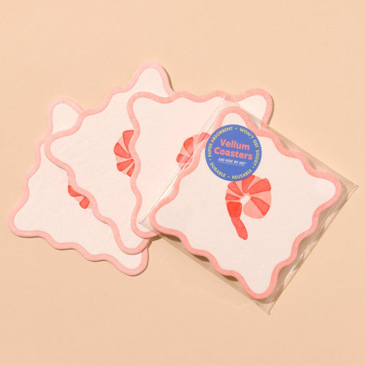 Set of pink coasters with a single shrimp design with a blue label on a beige background