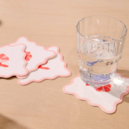 Set of coasters with shrimp design on a beige surface with a glass of water.