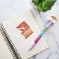 Sticker made to look like a bag of Asian shrimp chips, laying on top of a lined notebook with a rainbow pen 
