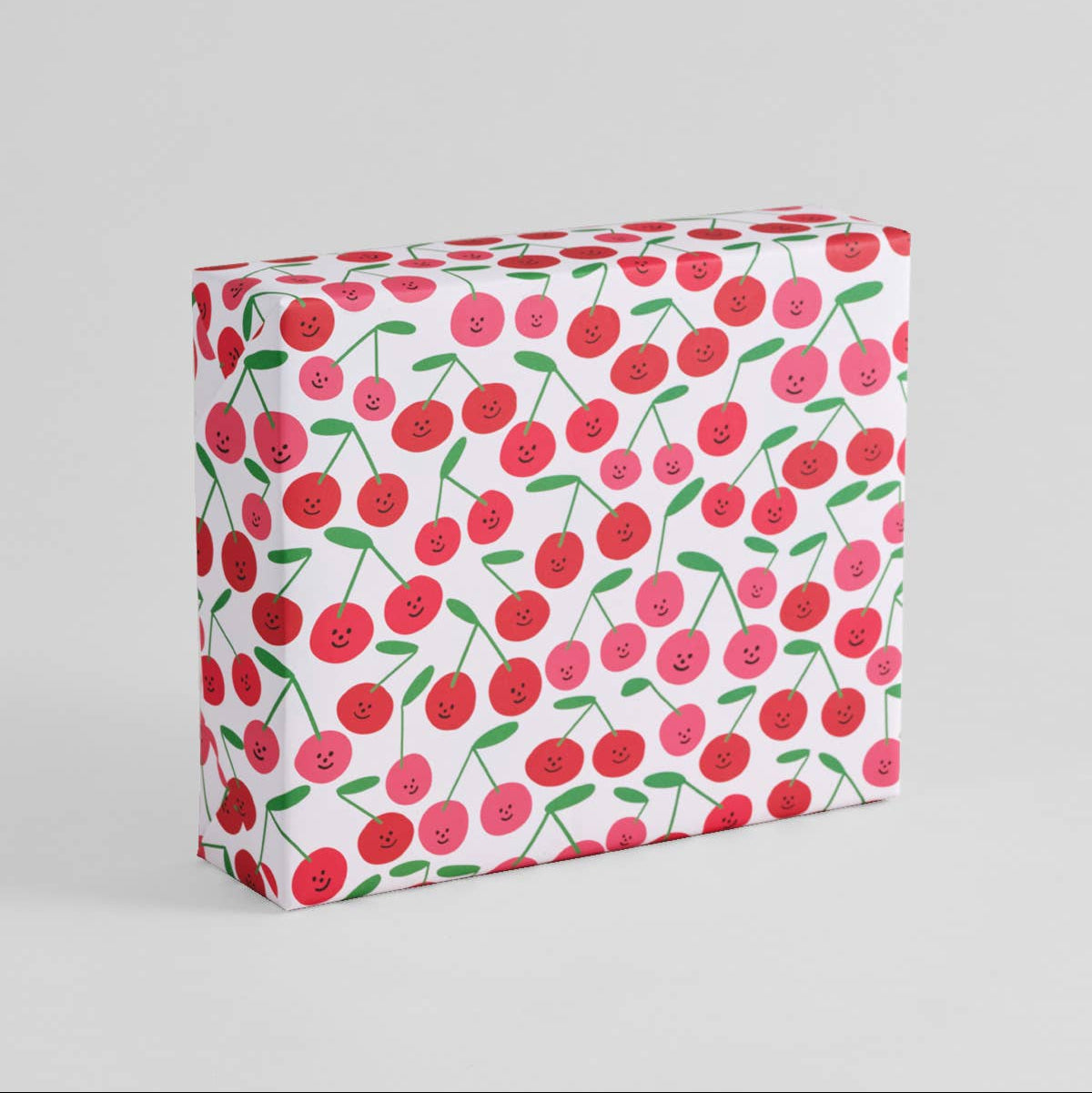 A box wrapped with a gift sheet with a smiley-faced cherry design all over 