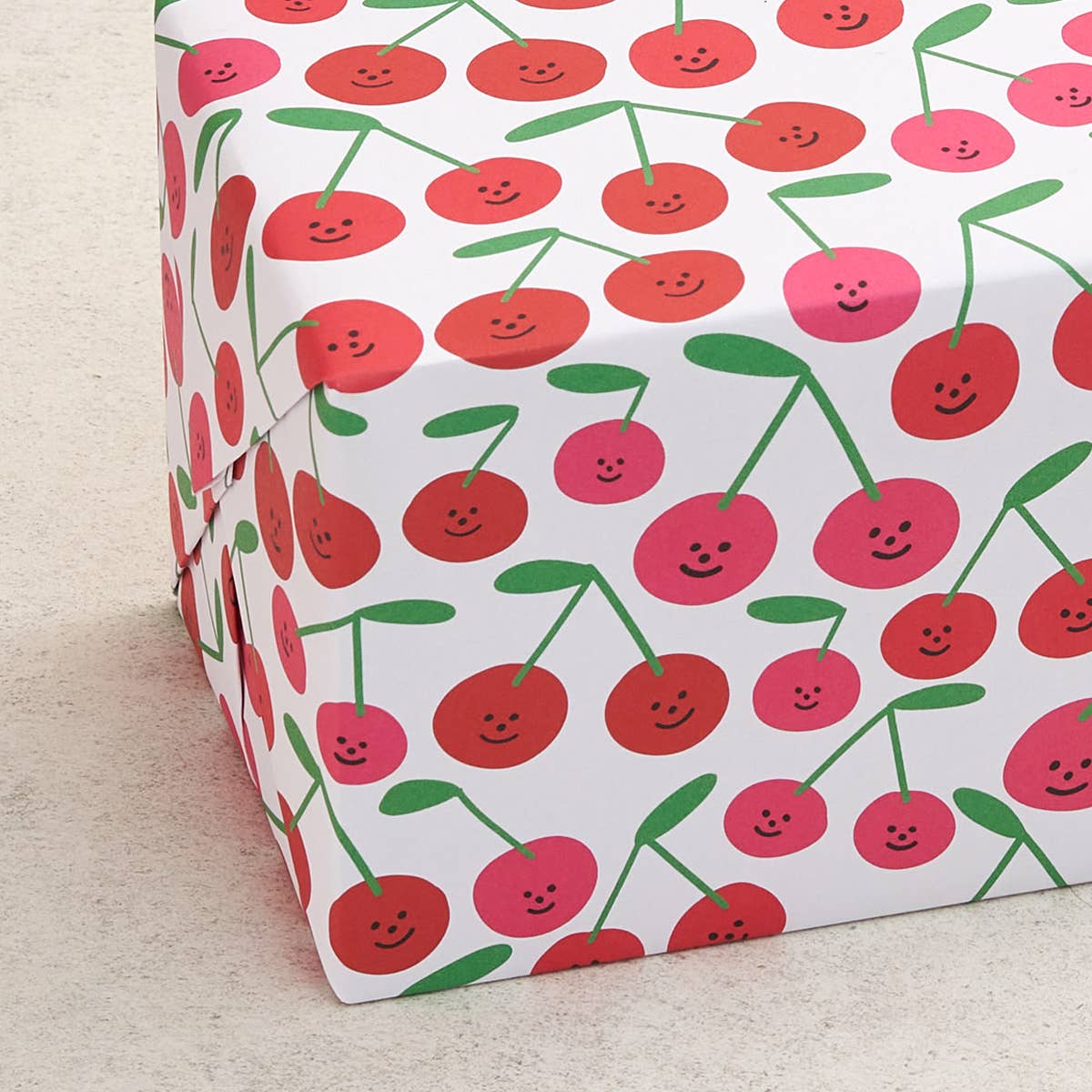 close up of the gift wrap sheet with a smiley-faced cherry design all over 