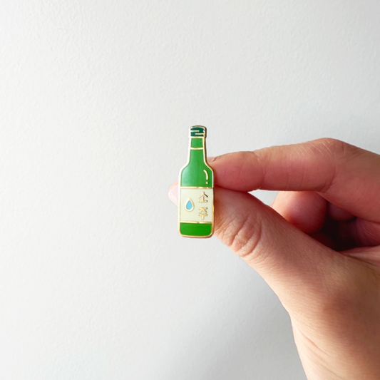 hand holding a soju bottle enamel pin