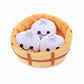 Plush soup dumplings in a steamer basket on a white background