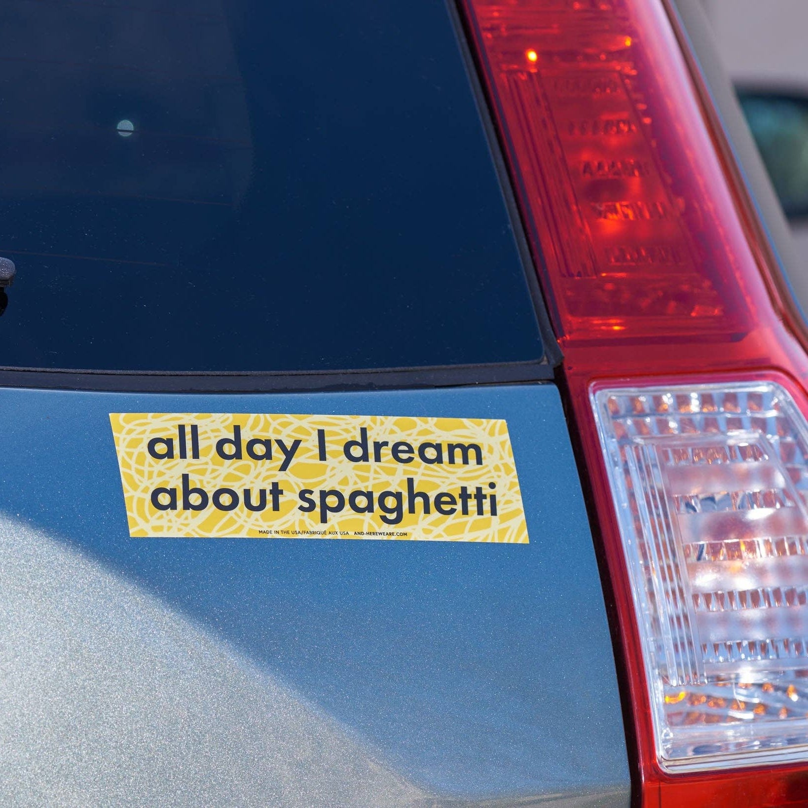 yellow bumper sticker that reads "all day I dream about spaghetti" on a car 