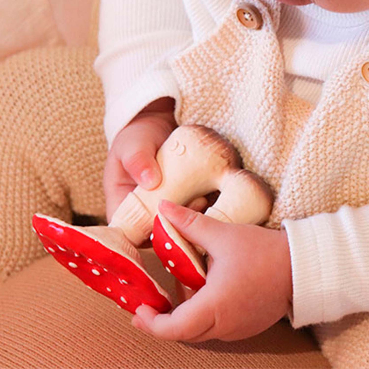 Photo of tiny chubby baby hands holding mushroom toy.