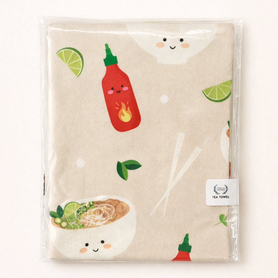 Beige tea towel with pho bowls and sriracha illustrations in packaging