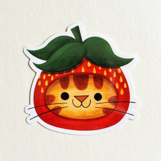 orange tabby cat wearing a strawberry hat 