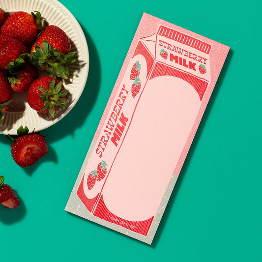 Strawberry milk carton with strawberries on a teal background