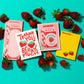 Notebooks with strawberry-themed designs and text on a turquoise background with strawberries.