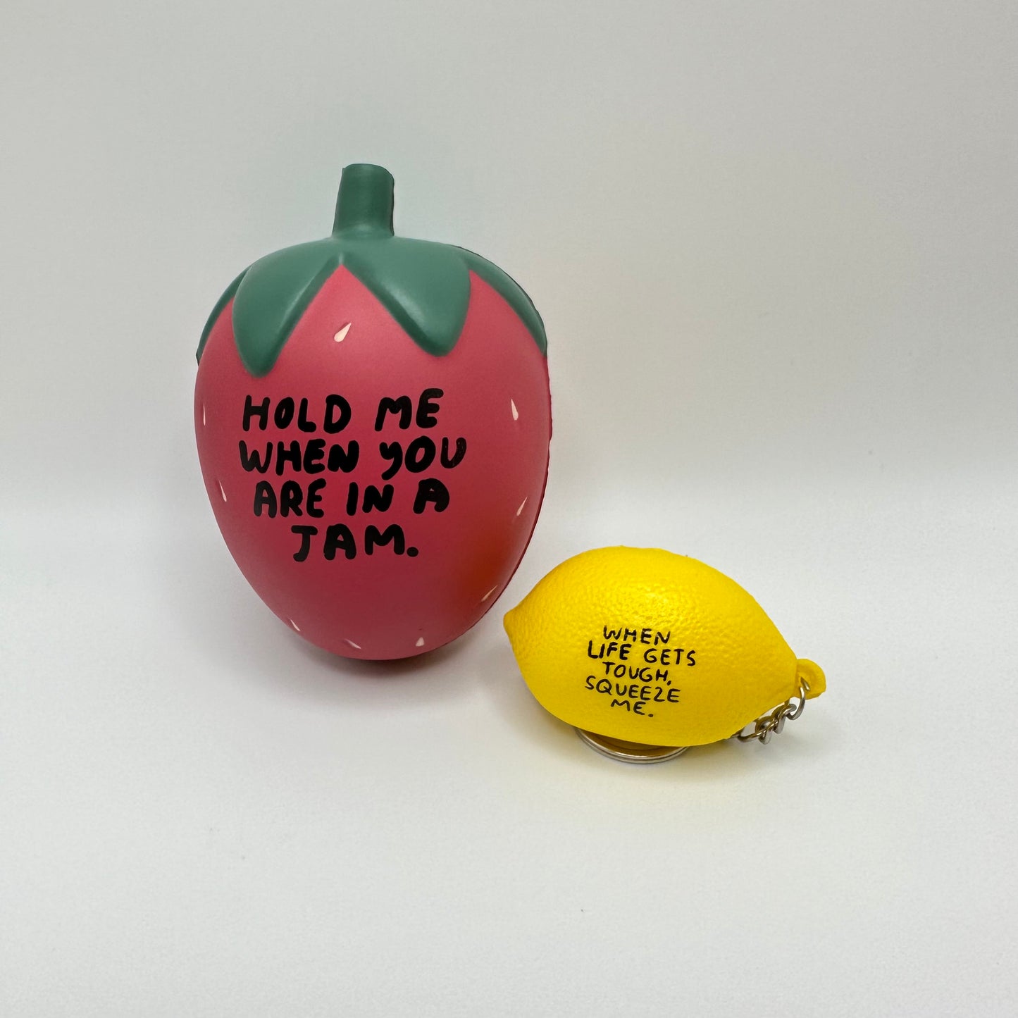 Two stress balls next to each other. Strawberry on the left and lemon keychain on the right.