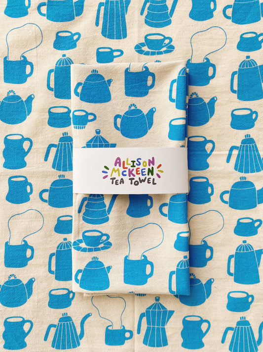 Tea towel with different styles of tea/coffee pots and mugs printed in blue ink on it