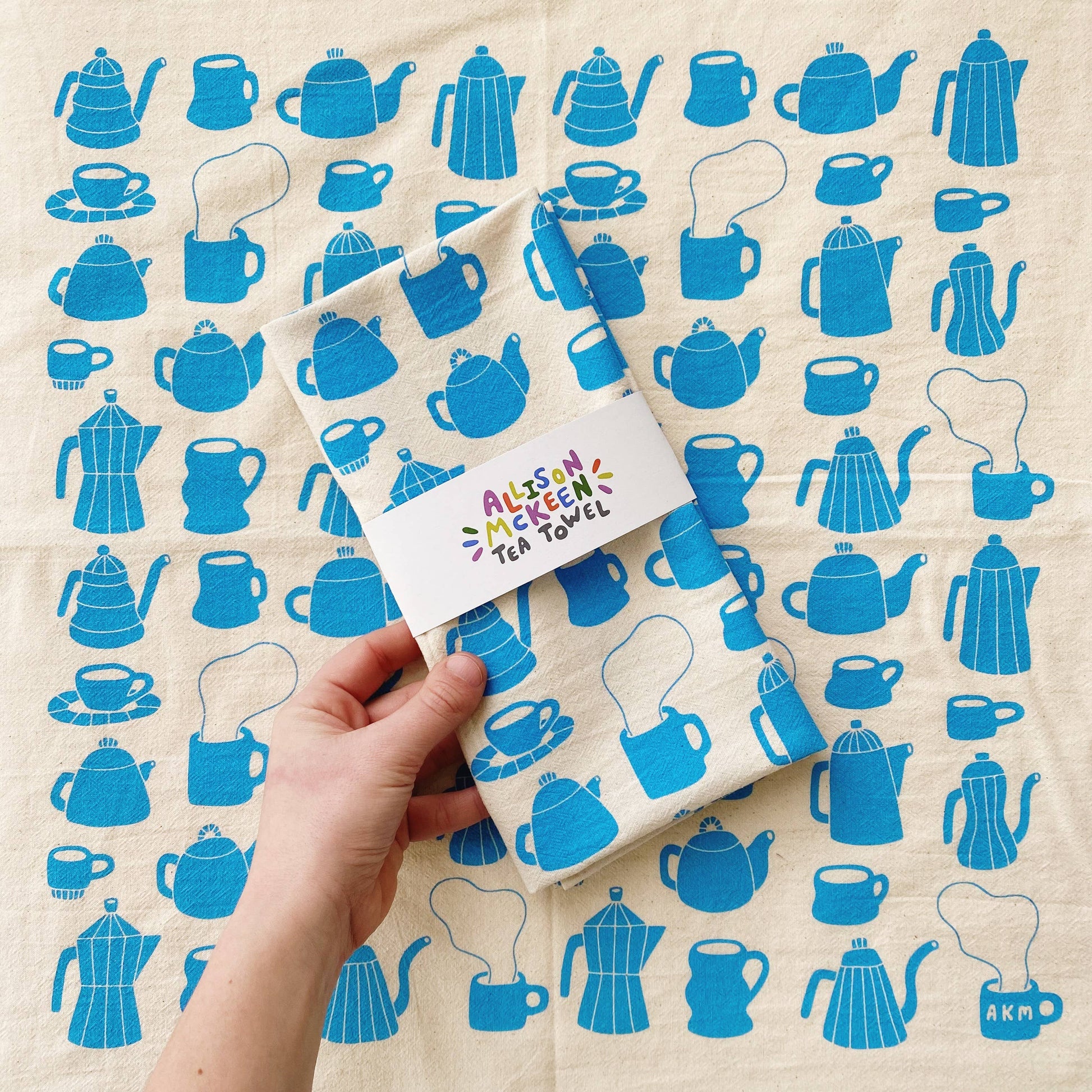 Tea towel with different styles of tea/coffee pots and mugs printed in blue ink on it