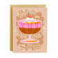 Greeting card with a dessert illustration and humorous text "thanks for pudding up with my kid" on a beige background