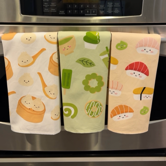 3 kitchen towels hung on oven handle -- bao, matcha and sushi