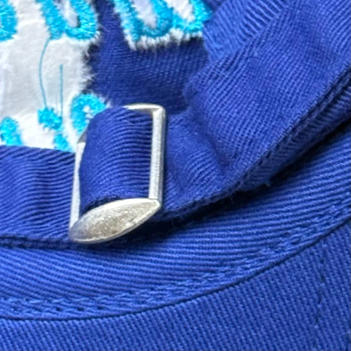 Close-up of a blue cap with a metal buckle on a textured background