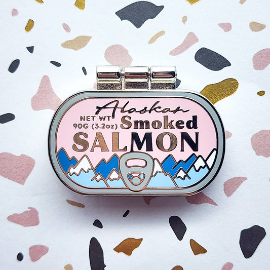 Alaskan Smoked Salmon container as an enamel pin, with mountain design on a colorful background