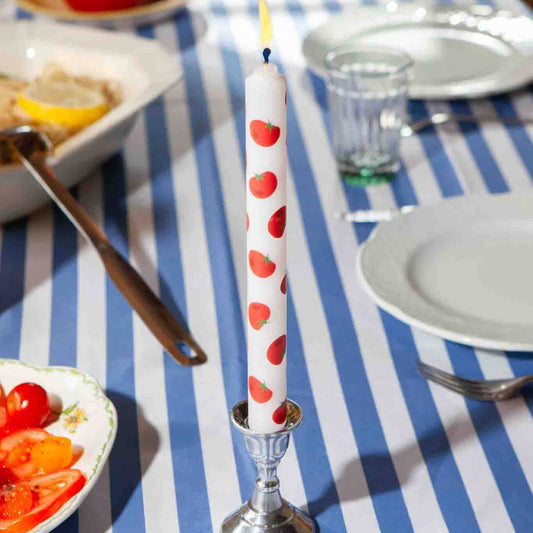 Taper candle with tomato pattern on a striped tablecloth