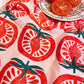 pink kitchen towel with repeated pattern of a half-cut tomato 
