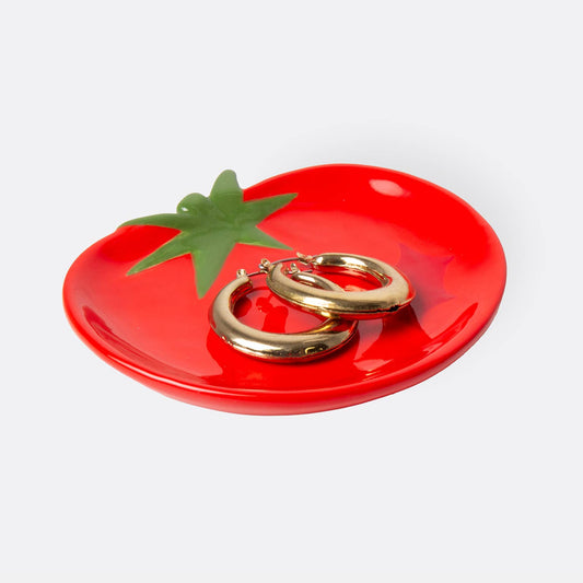 Red tomato-shaped trinket dish with gold rings on a white background