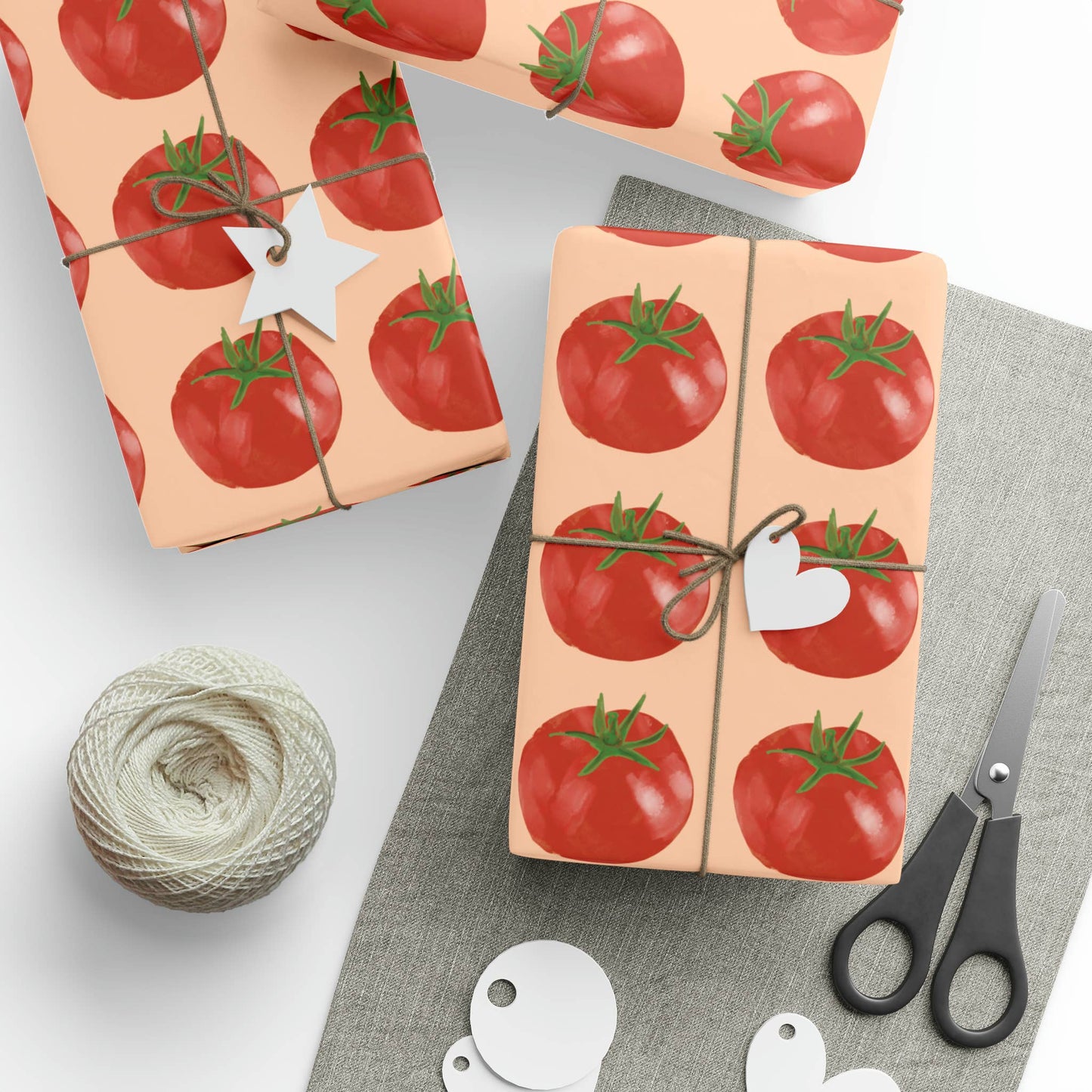 Gift wrap with tomato pattern, scissors, and yarn on a light background