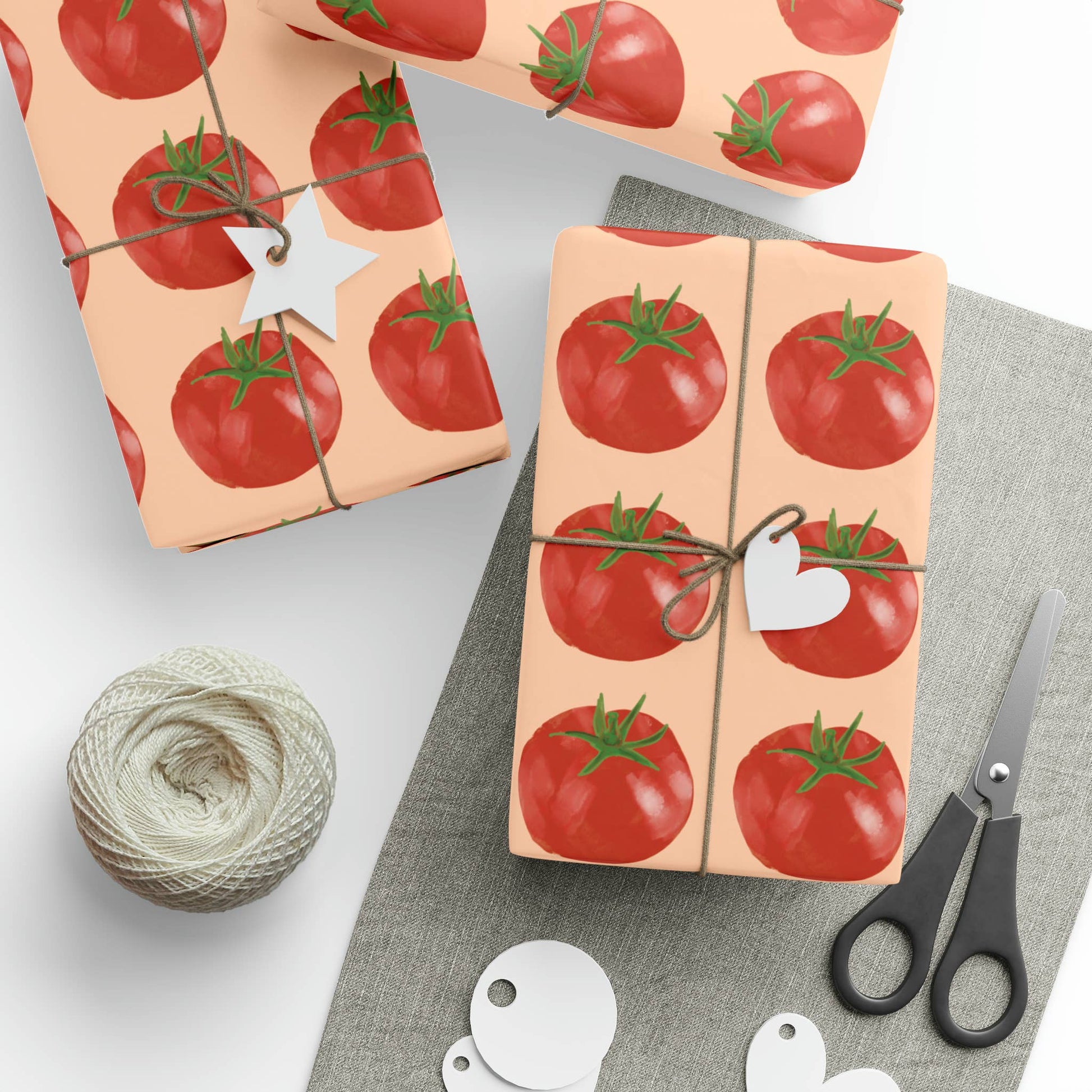 Gift wrap with tomato pattern, scissors, and yarn on a light background