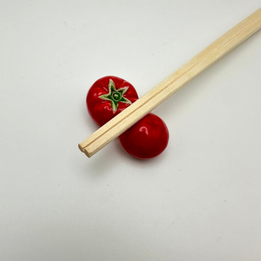 Two tomato chopstick holder with chopsticks.