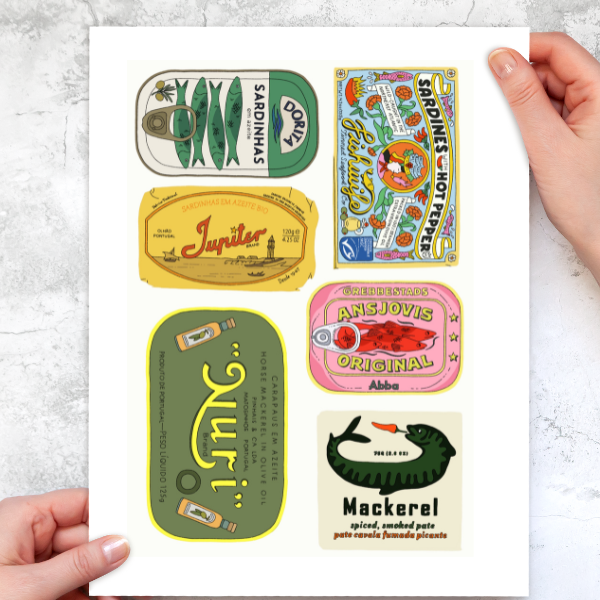 Collection of vintage-style fish can stickers held by a person on a light gray background