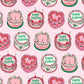 roll of wrapping paper with a continous pattern of birthday cakes decorated in a vintage style. Color theme are pinks, reds, whites and greens 