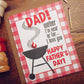 Father's Day card with BBQ design and text on a wooden surface