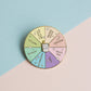 Colorful enamel pin with boba/bubble tea flavor options on a pastel background