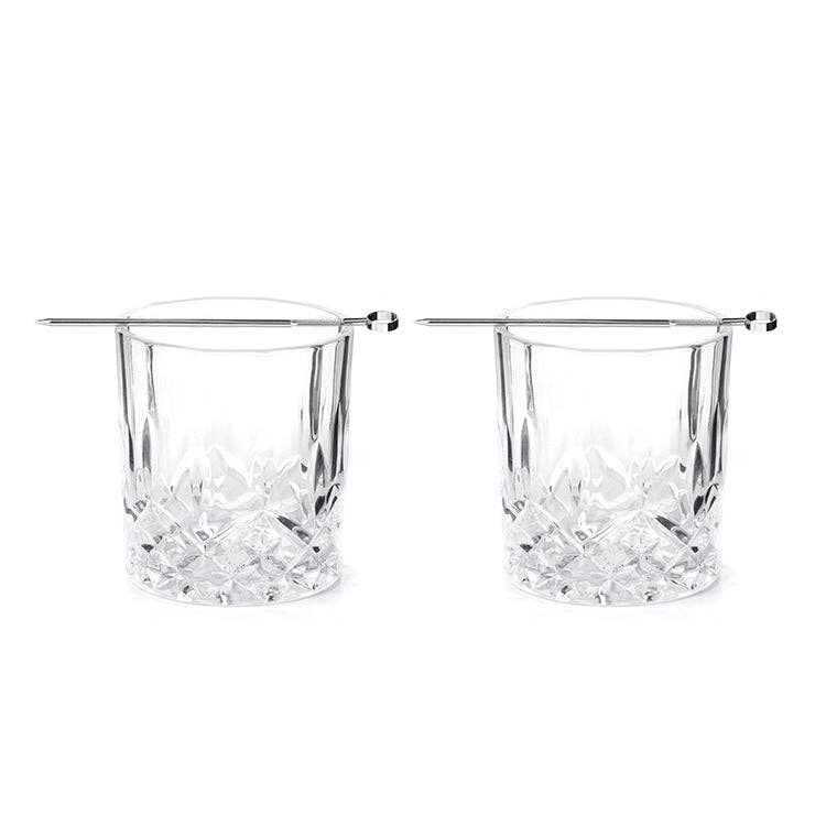 Two clear whiskey glasses with silver picks sitting on top of each one on a white background