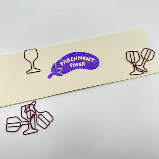 Wine glass paperclips in a pile and one clipped to a piece of paper.