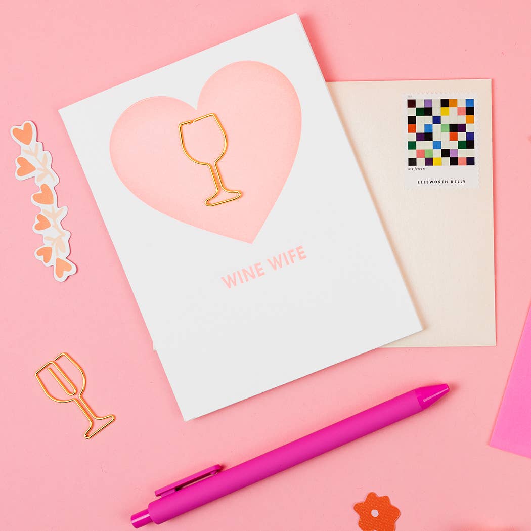 Greeting card with 'Wine Wife' design, pink pen, and decorative items on a pink background