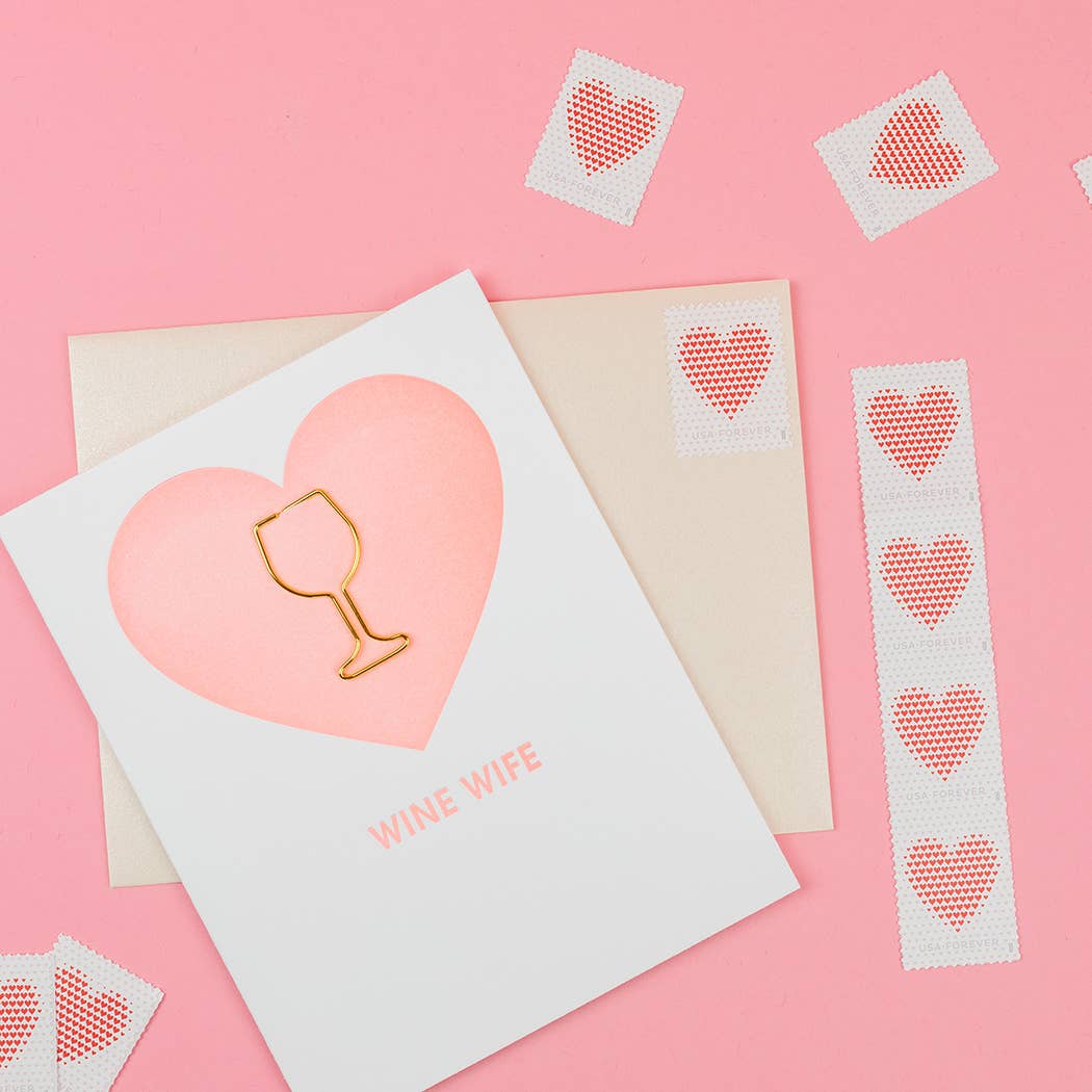 Card with pink heart and gold wine glass paper clip on a pink background