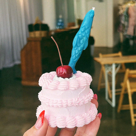 A single, blue sardine birthday candle on top of a mini cake 