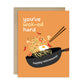 Greeting card with a wok of noodles and text that says "you've wok-ed hard. Happy retirement!" on an orange background