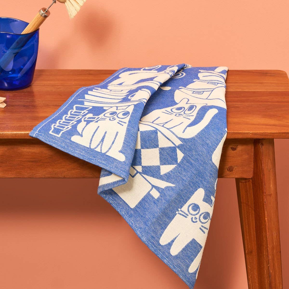 image of a folded "kitchen cats" tea towel on top of a wooden table 