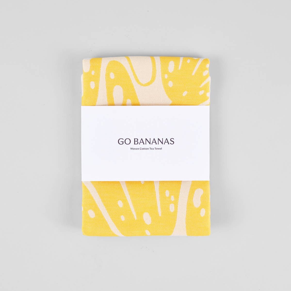 yellow "go bananas" kitchen towel wrapped in paper band packaging