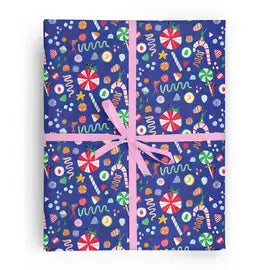 Box wrapped in blue wrapping paper that features a variety of candies and tiny people tumbling around in santa hats. Tied with a pink ribbon. 