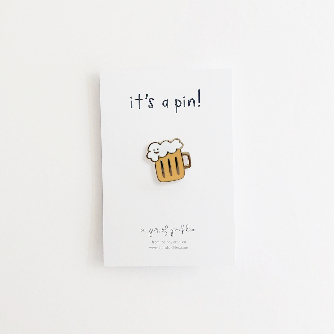 Illustrated beer mug with foam enamel pin on a white card backing that says "it's a pin!"