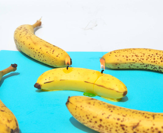 Banana candle shown in a group with real bananas.