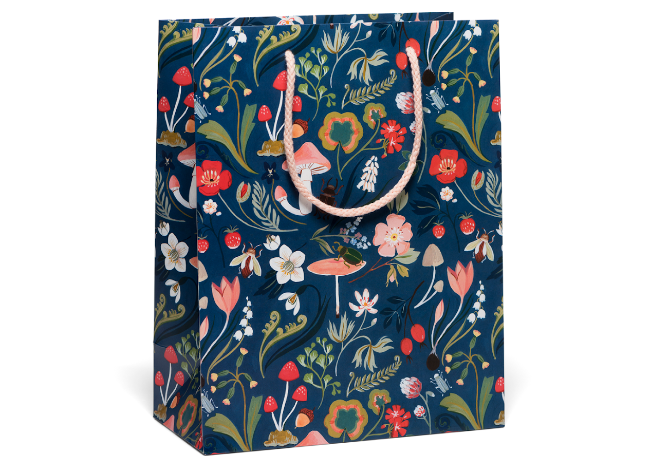 Blue gift bag with various forest foliage, plants and creatures on it 