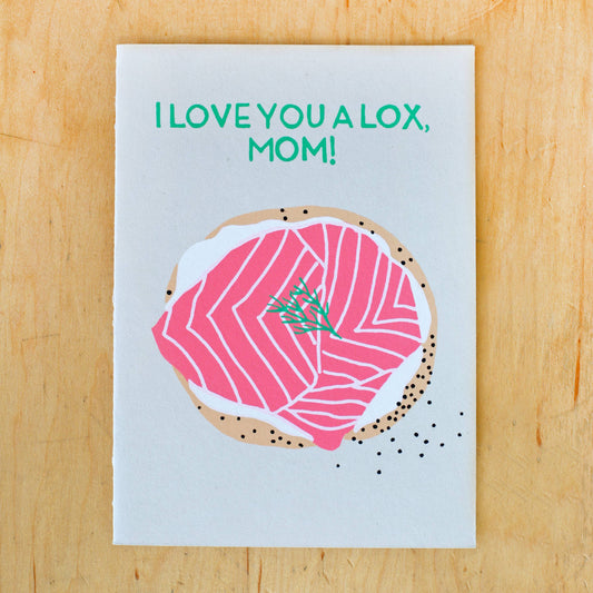 Card reads "I love you a lox, mom!" and has illustration of a bagel with cream cheese, lox and dill on it 